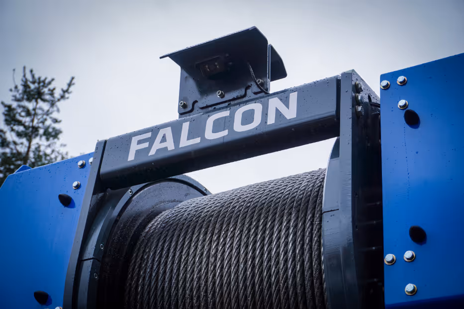 Close-up of a blue industrial winch labeled 'FALCON' with coiled steel cable.