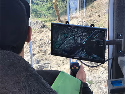 Person operating a device with a monitor showing a detailed view of ground debris or sticks.