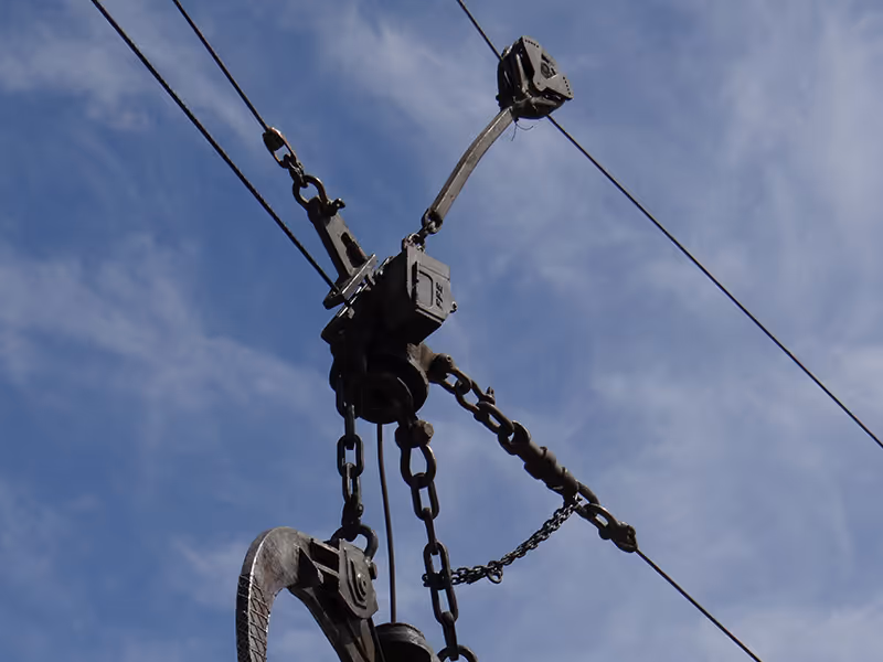 Close-up of a metal grapple hook attached to cables against a blue sky background.