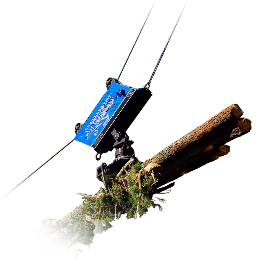 Blue mechanical grapple lifts a bundle of tree logs in a forested area under clear blue sky.