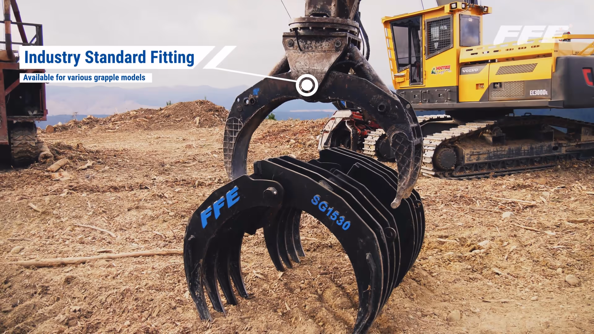 Excavator grapple attachment lifting FFE SG1530 grapple rake on dirt ground.