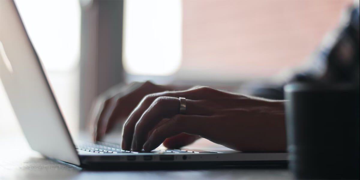 close up of hands typing on a laptop keyboard