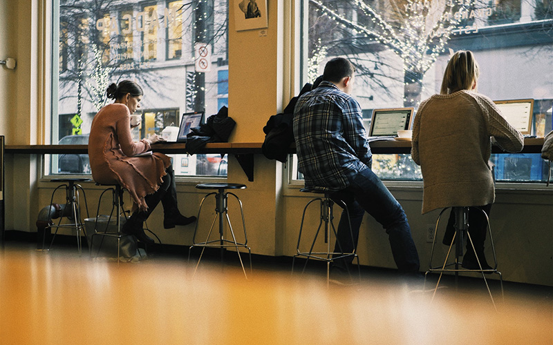 People in a coffee shop use public wi-fi