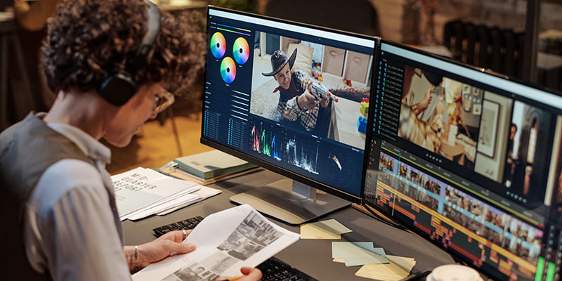 A video editor reviews a storyboard in front of her computer