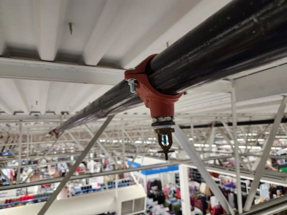 Red industrial piping system with vertical black pipes, pressure gauges, valves, and control devices in a utility room.