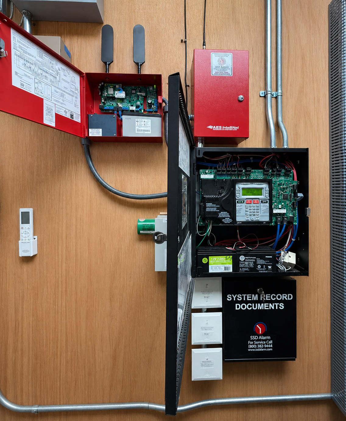 Red industrial piping system with vertical black pipes, pressure gauges, valves, and control devices in a utility room.