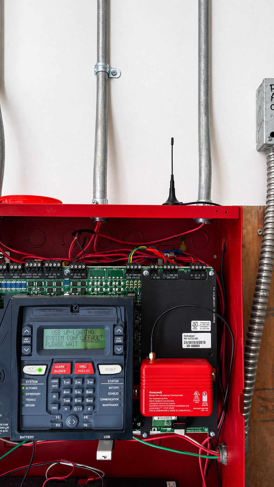 Technician in a Spectrum Fire Protection hoodie working on industrial pipes and gauges in a utility closet.