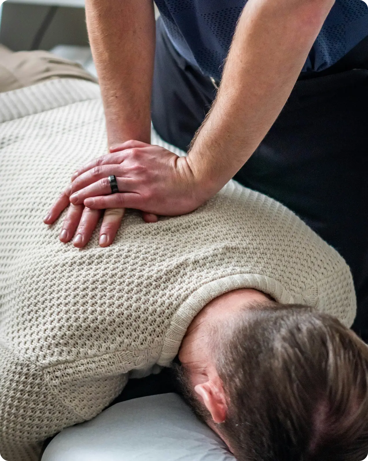 Person receiving a back massage or chiropractic adjustment on a beige sweater.