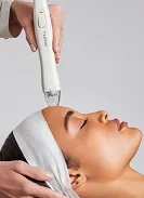 Close-up of a woman receiving a facial treatment with a handheld skincare device.