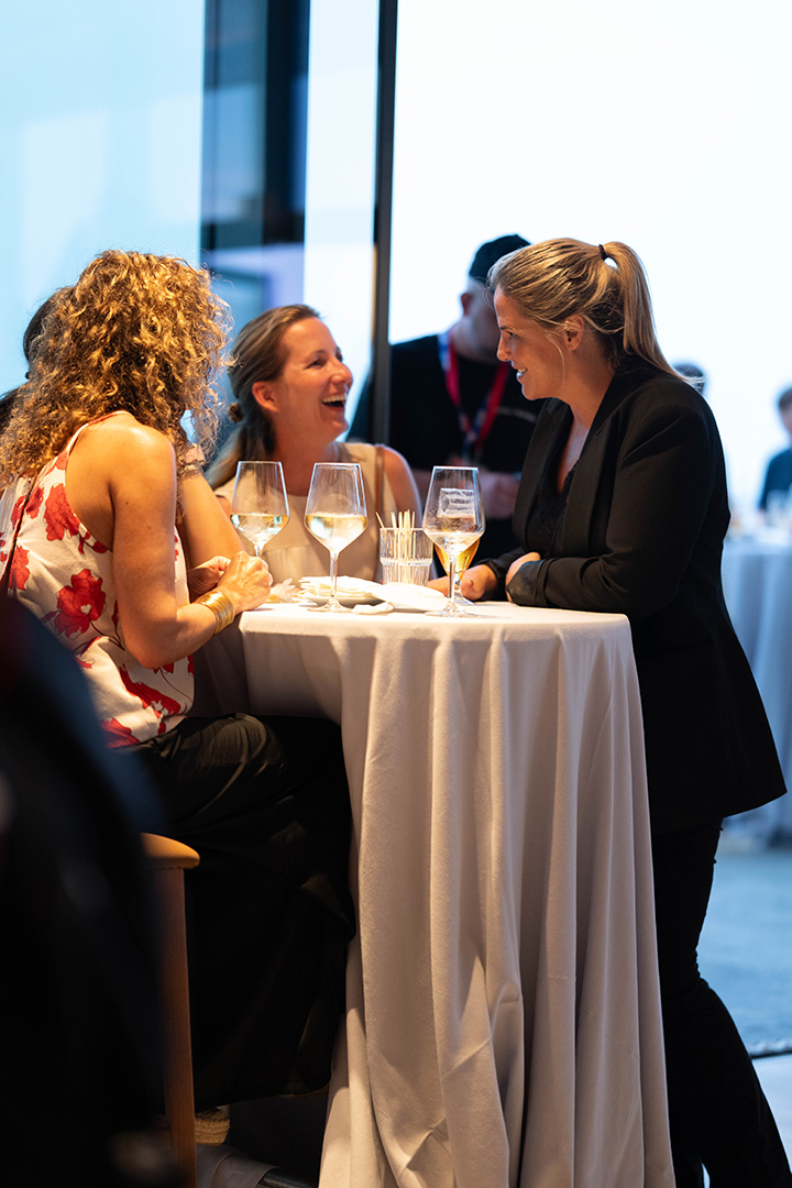 Event guests speaking at a cocktail table during a professional hospitality reception.