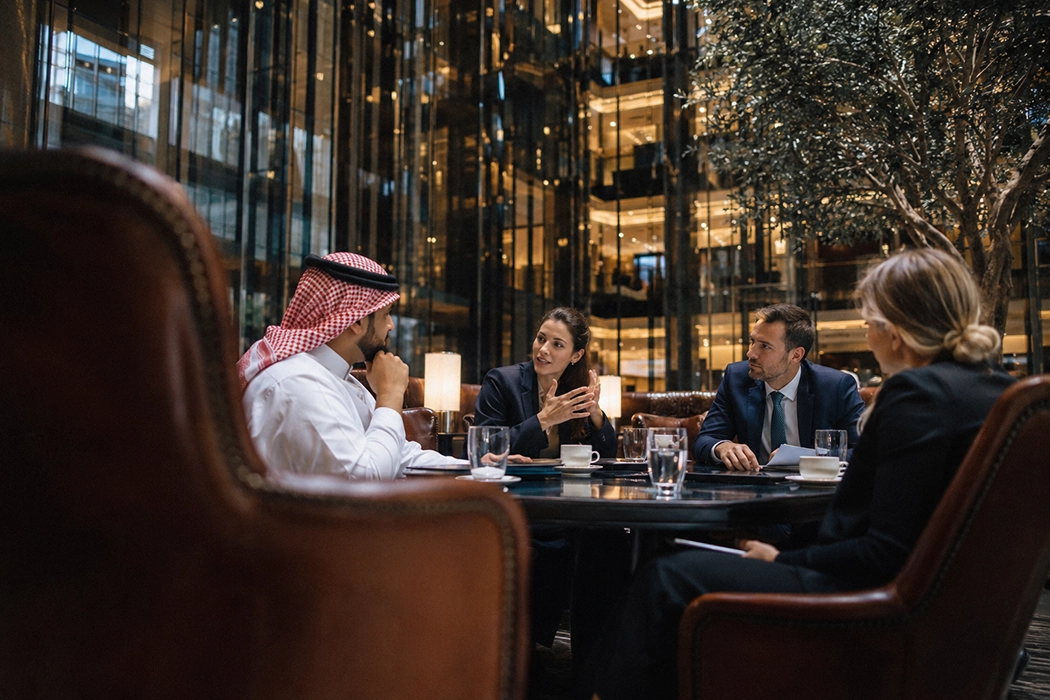 International event accommodation team meeting with clients in a hotel lounge to coordinate tailored logistics.