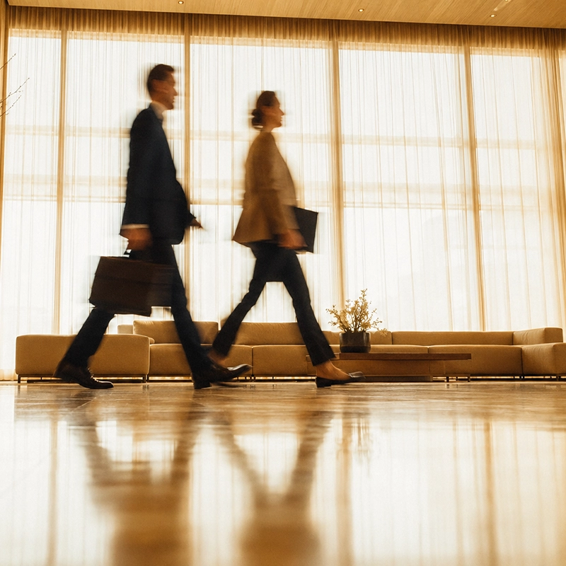 A man and a woman walking a hotel lobby during a business trip.