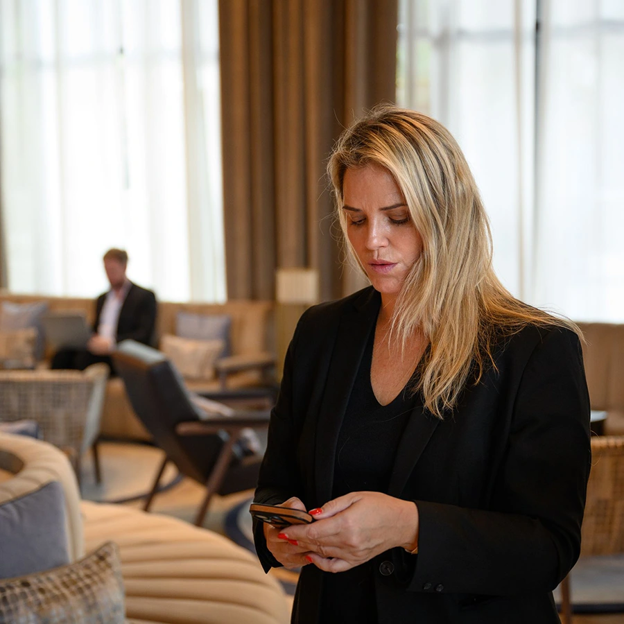 A woman checking her phone in a hotel lobby.