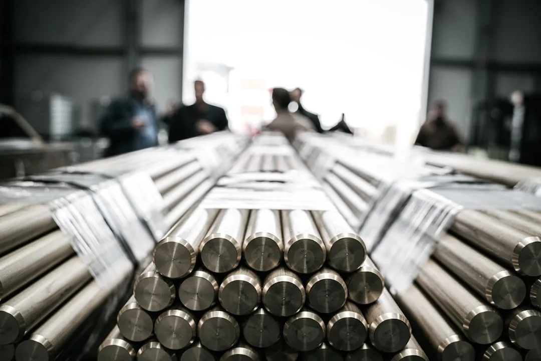 a group of people standing around a pile of metal rods. Photo by Kasper Gant on Unsplash