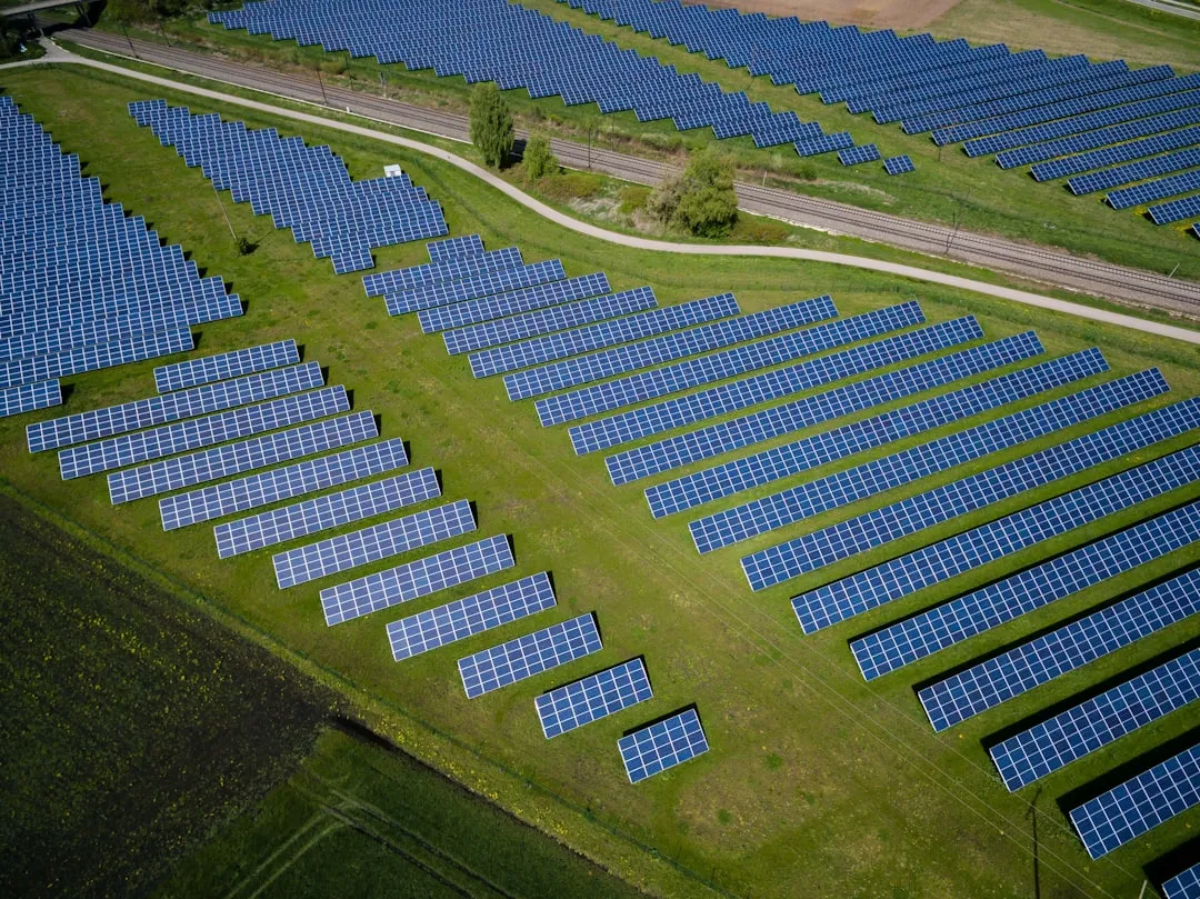 aerial photography of grass field with blue solar panels. Photo by Andreas Gücklhorn on Unsplash