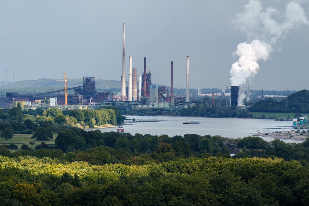 Industrial complex with smokestacks near a body of water. — Photo by Jakub Żerdzicki on Unsplash