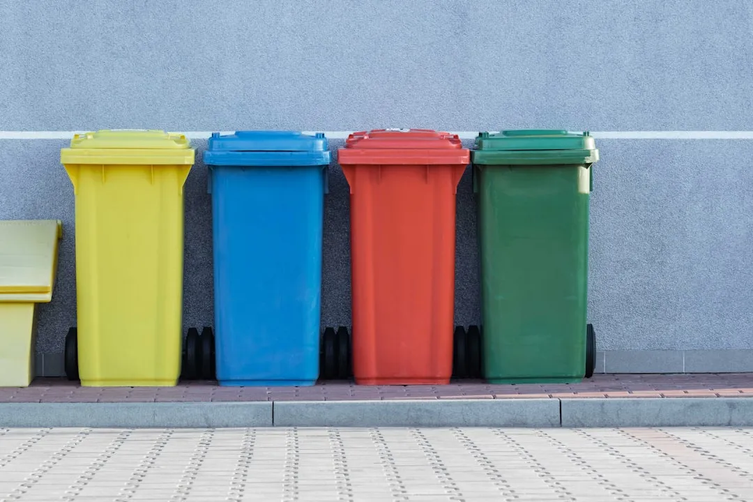 four assorted-colour trash bins beside grey wall. Photo by Pawel Czerwinski on Unsplash