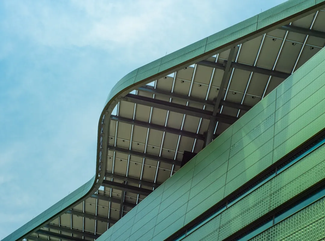 green and black glass walled building under blue sky during daytime. Photo by the blowup on Unsplash