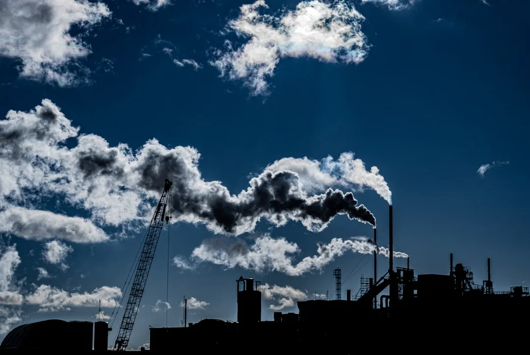 a factory with smoke coming out of it's stacks. Photo by chris robert on Unsplash