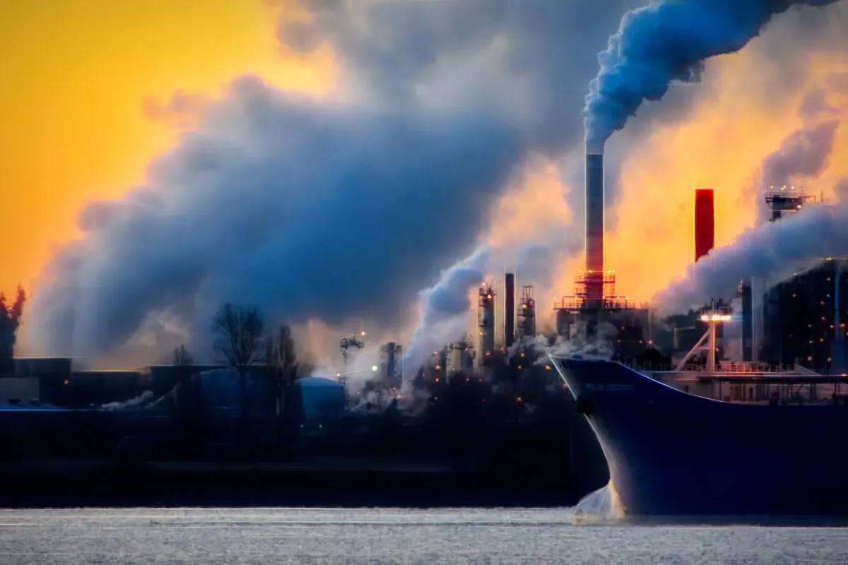a large boat in a body of water near a factory. Photo by Chris LeBoutillier on Unsplash