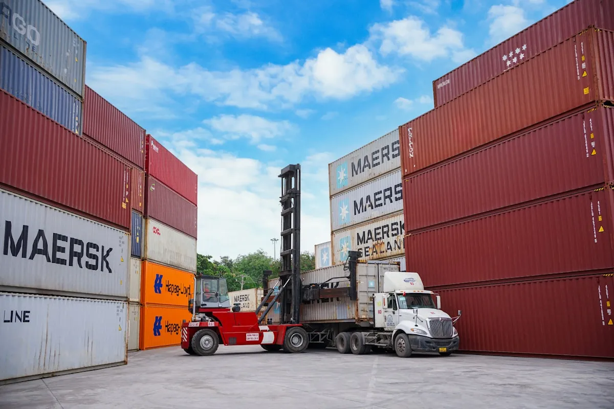 Forklift moving shipping containers at a port.. Photo by Solømen on Unsplash