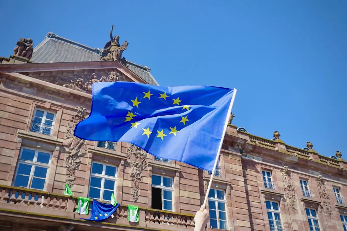 a flag on a pole in front of a building. Photo by Antoine Schibler on Unsplash
