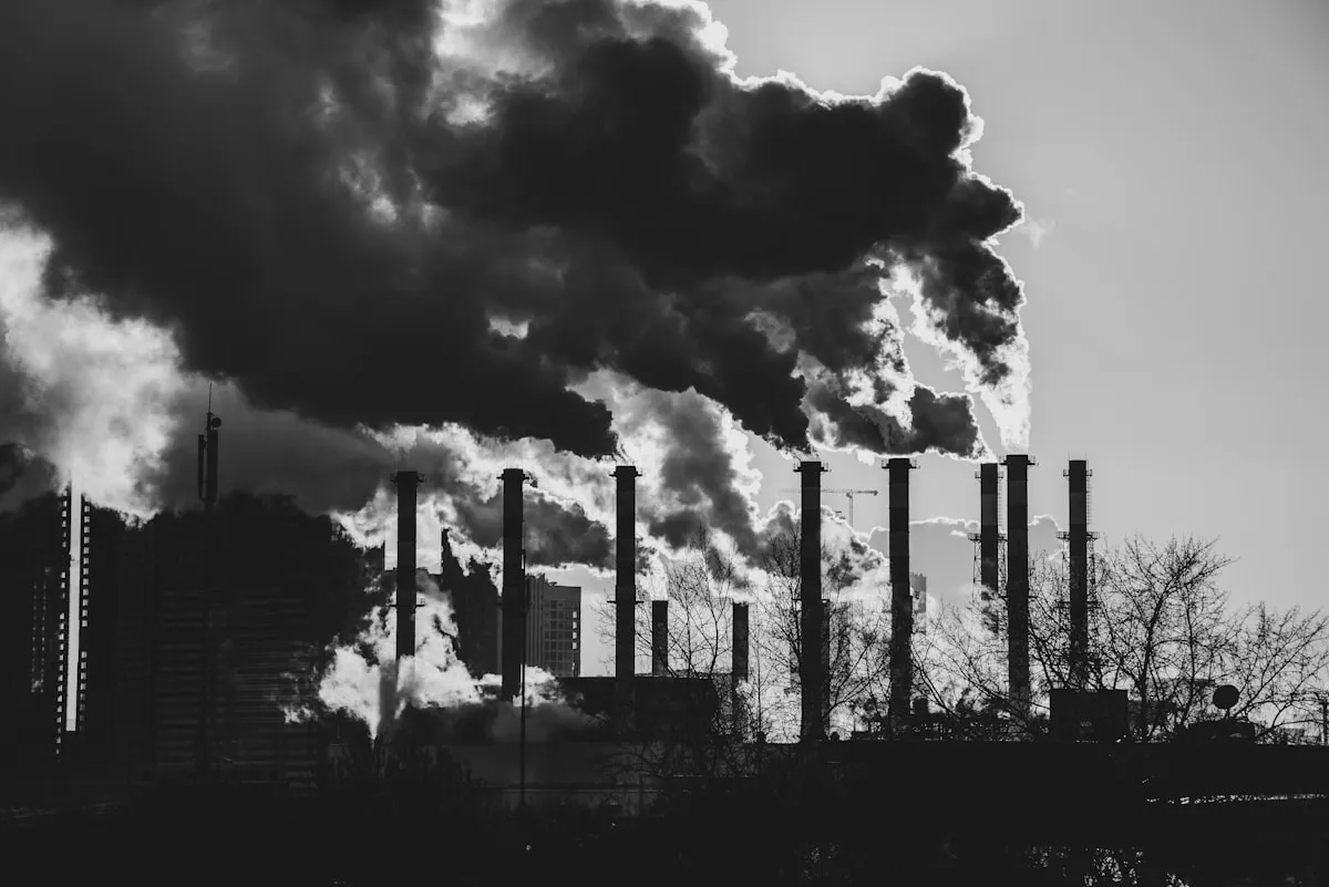 a black and white photo of smoke coming out of a factory, Photo by Сергей Крылов on Unsplash