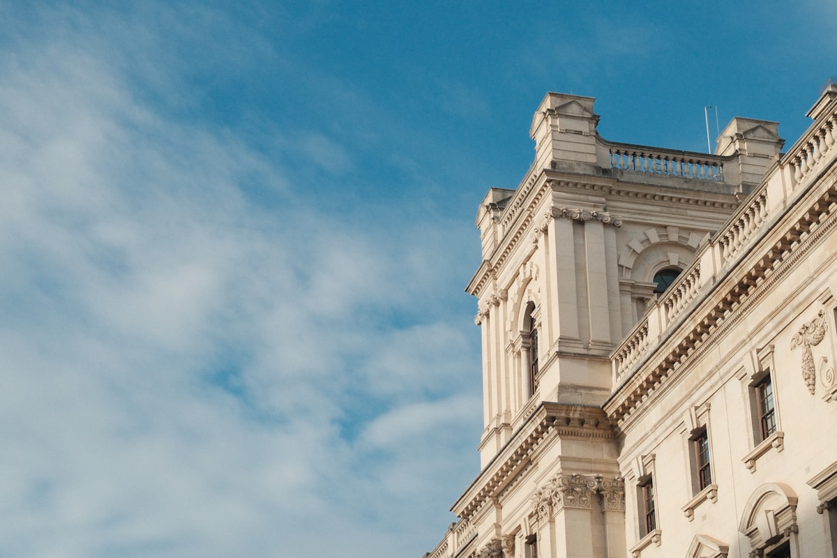 Ornate white building facade against a blue sky, Photo by Miralem-Davy Copra on Unsplash
