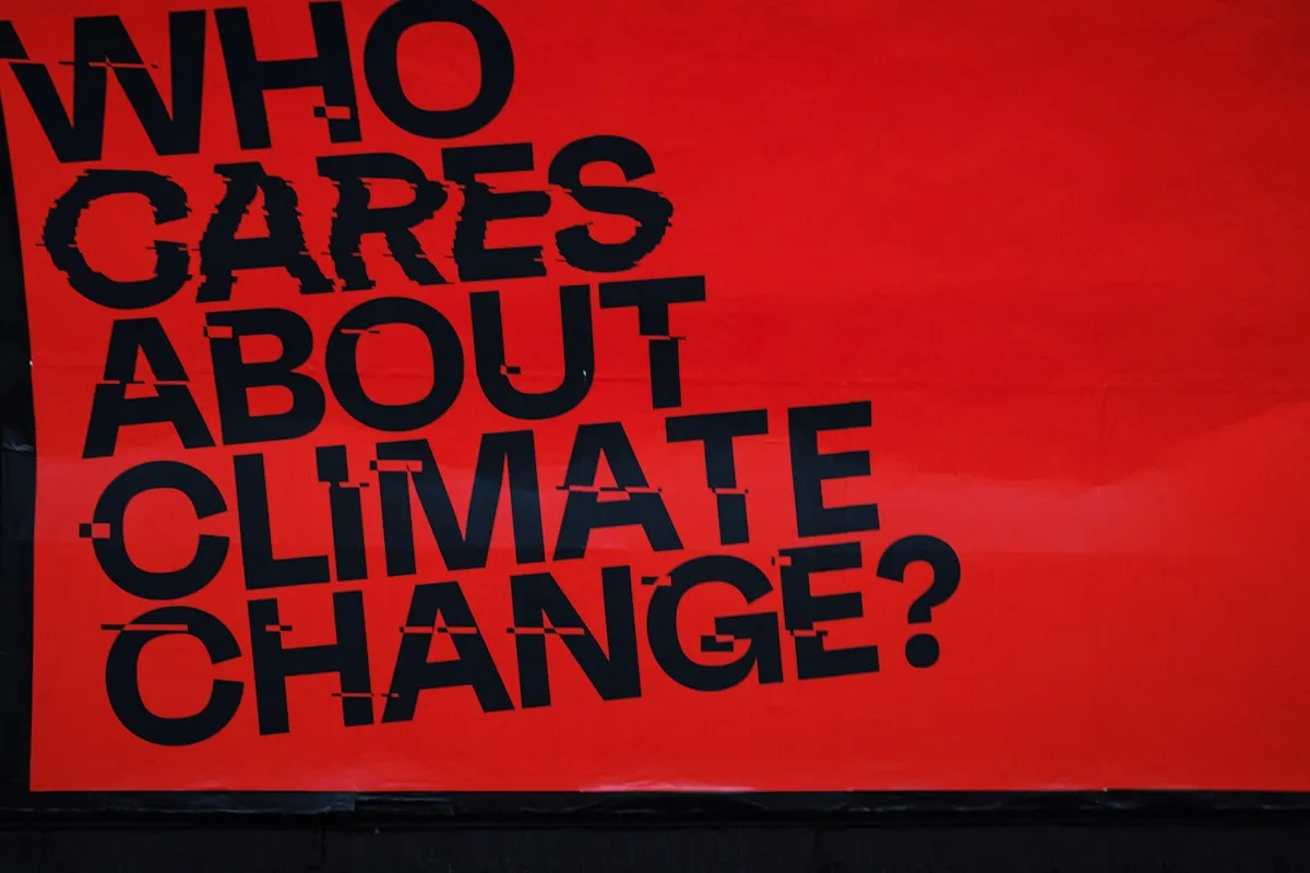 a red sign that says who cares about climate change?, Photo by Samuel Regan-Asante on Unsplash