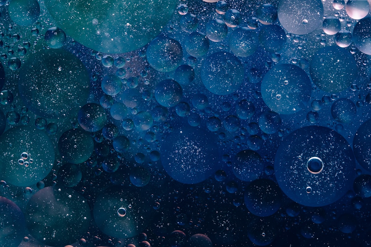 a close up of water bubbles on a blue surface, Photo by Rodion Kutsaiev on Unsplash
