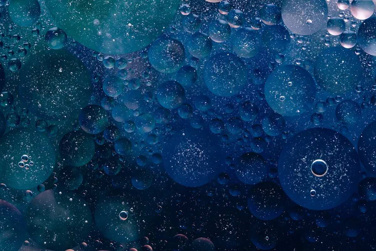 a close up of water bubbles on a blue surface, Photo by Rodion Kutsaiev on Unsplash