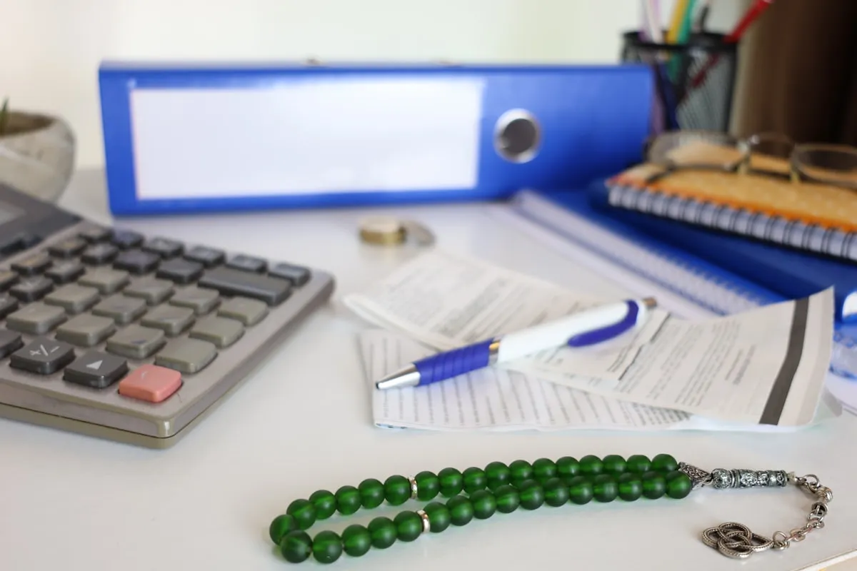 Desk with calculator, papers, and prayer beads., Photo by Cht Gsml on Unsplash