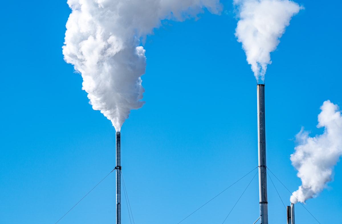 a smokestack emits from the top of a building. Photo by chris robert on Unsplash