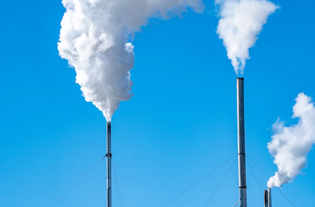 a smokestack emits from the top of a building. Photo by chris robert on Unsplash