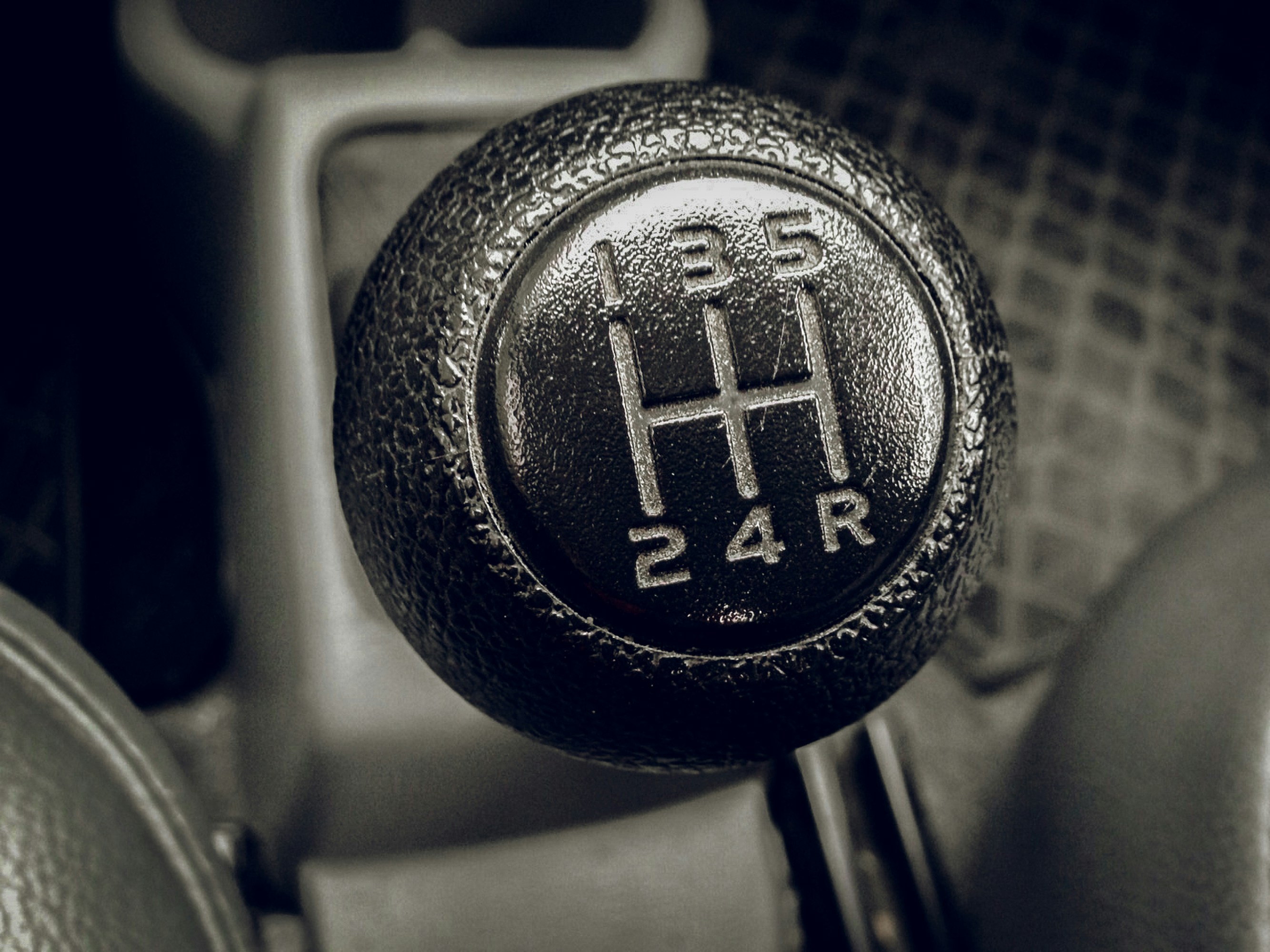 Close-up of a manual gearstick knob showing the five-speed shift pattern