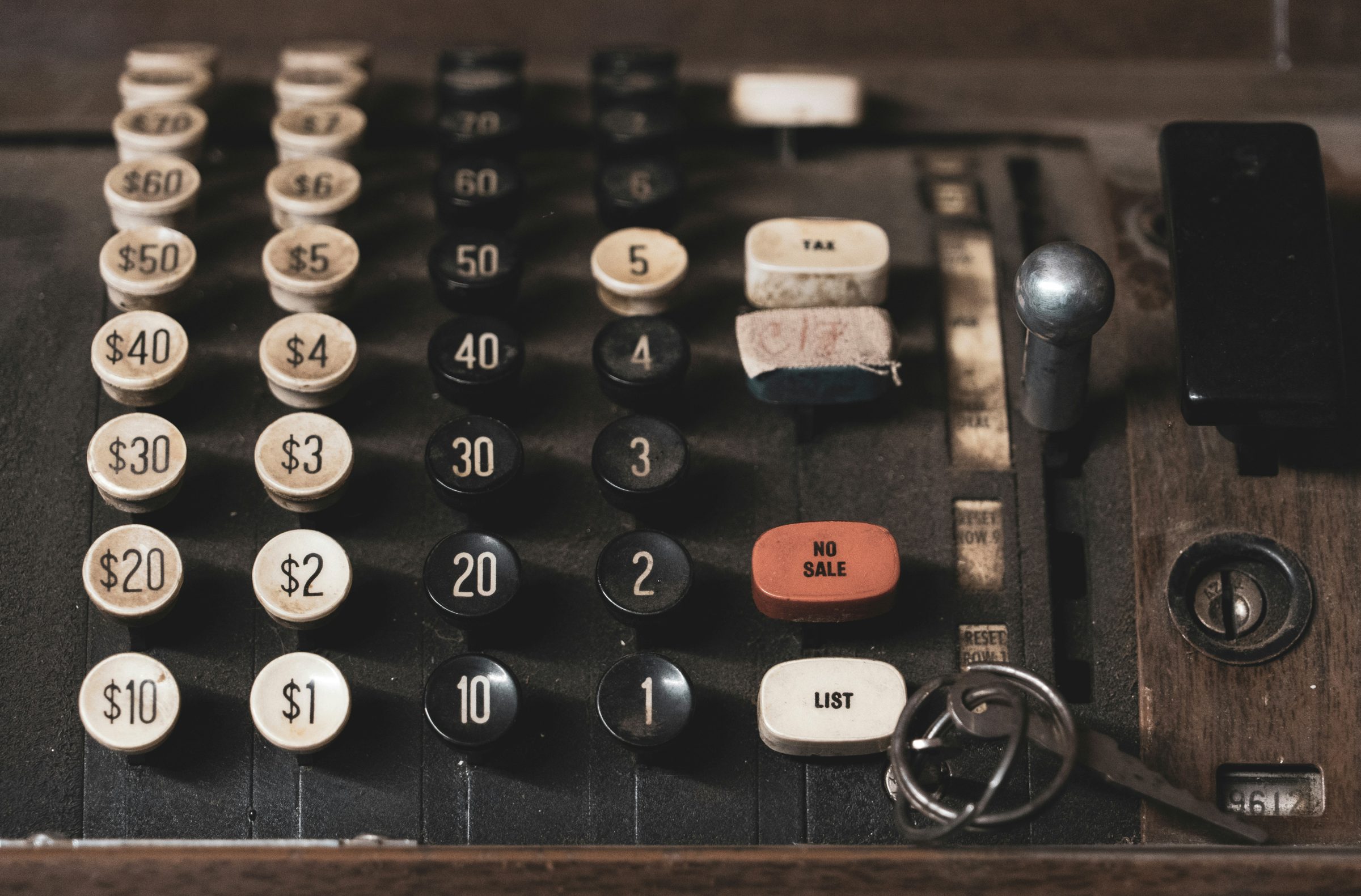 Close-up of the dollar-denominated keys of a vintage cash register, including a red No Sale button