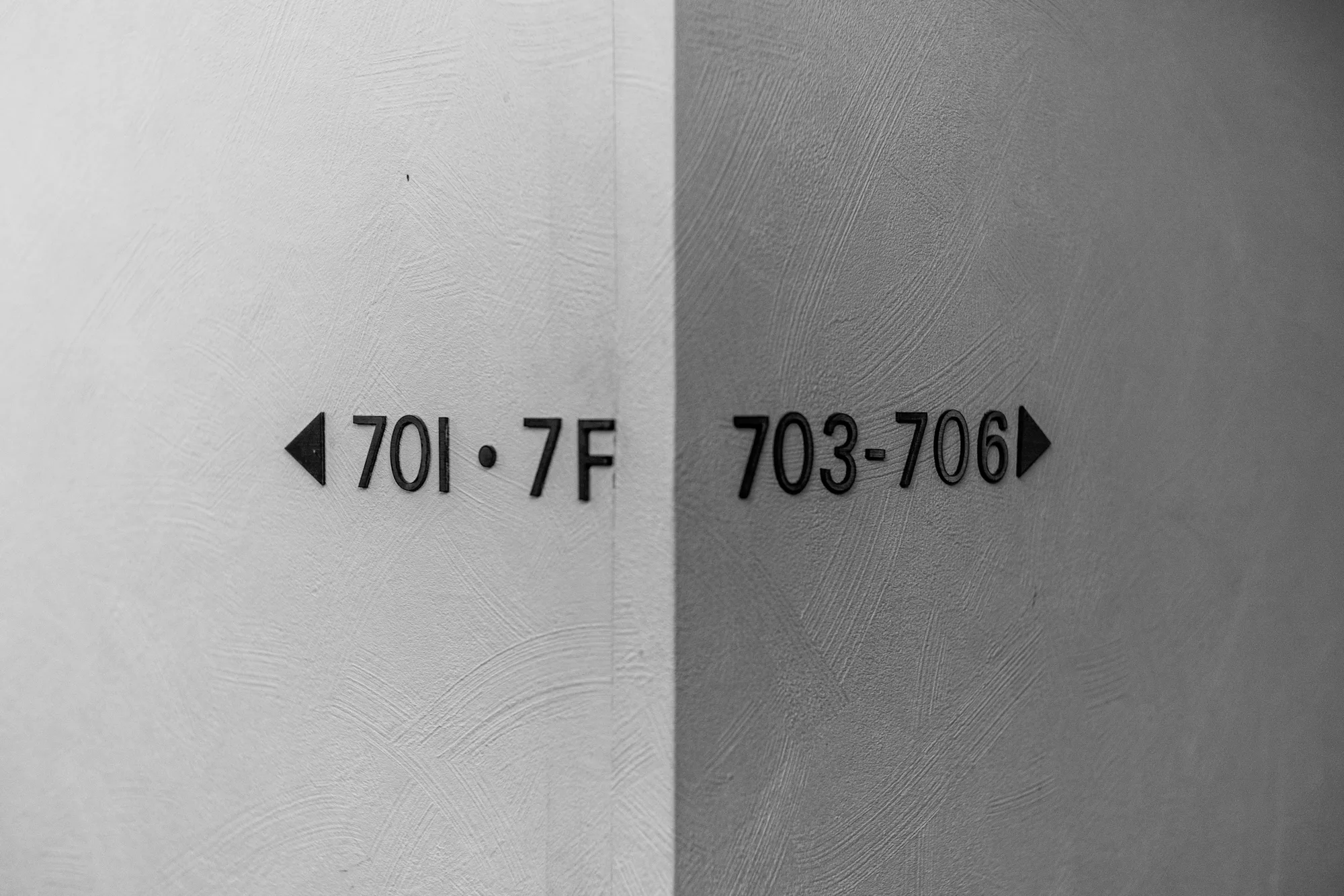 Black and white wall sign with arrows pointing to rooms 701 and 703 to 706 on the seventh floor
