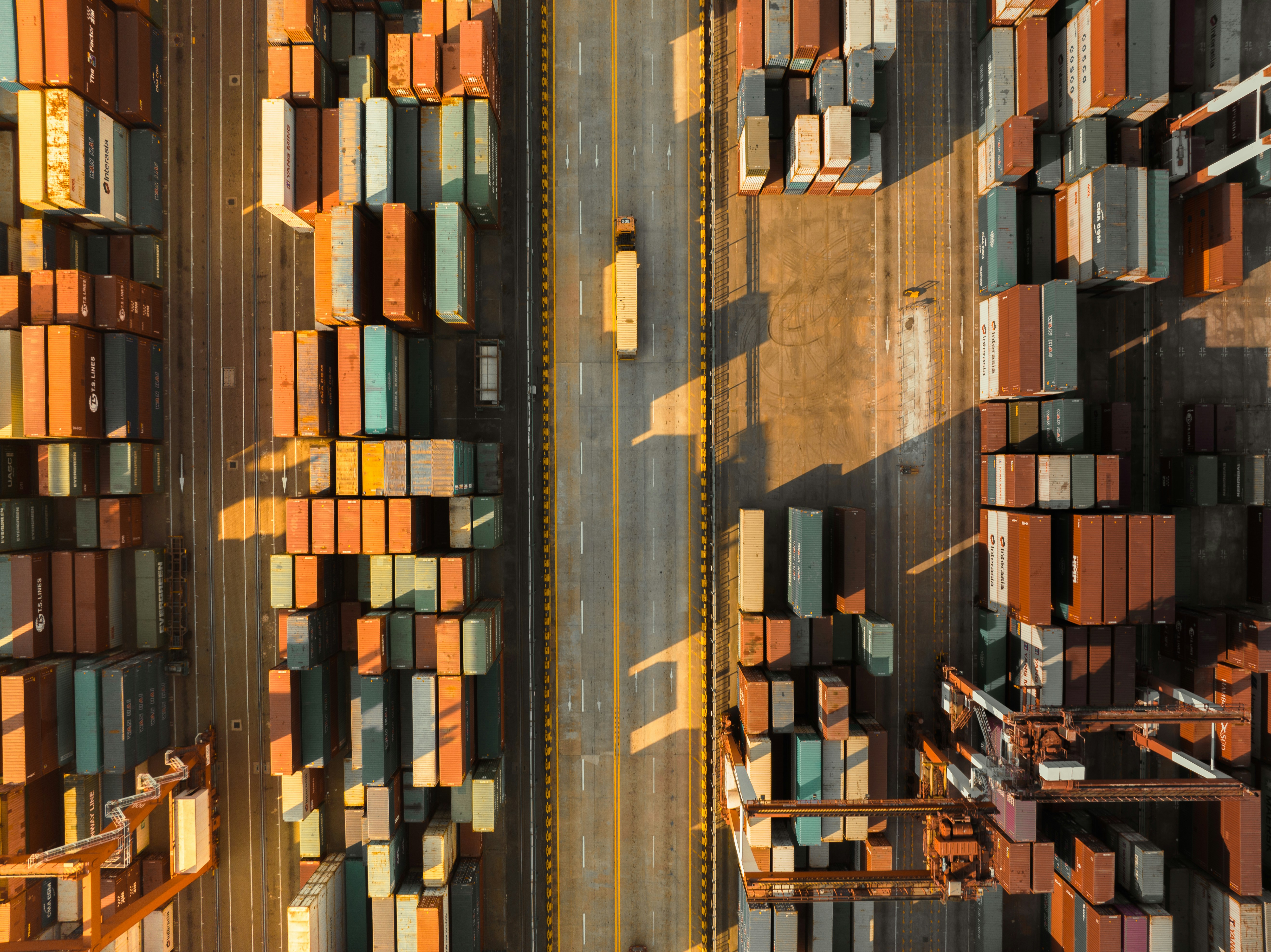 Aerial view of a container port with stacks of shipping containers either side of a road