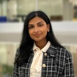 Ilakia Amirthalingam, smiling, with long dark hair, in a cream blouse and checked jacket