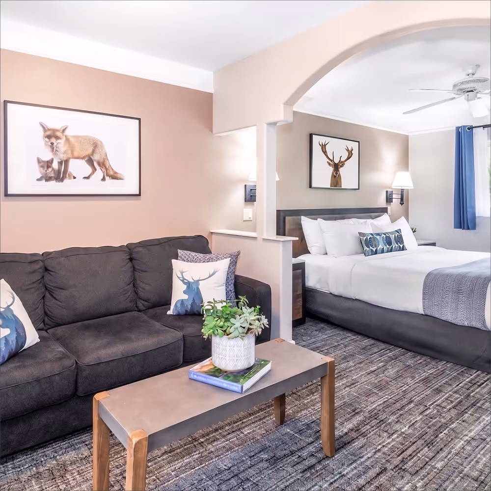 The sitting nook beside the bed — sofa, coffee table, and a quiet fox print on the wall.