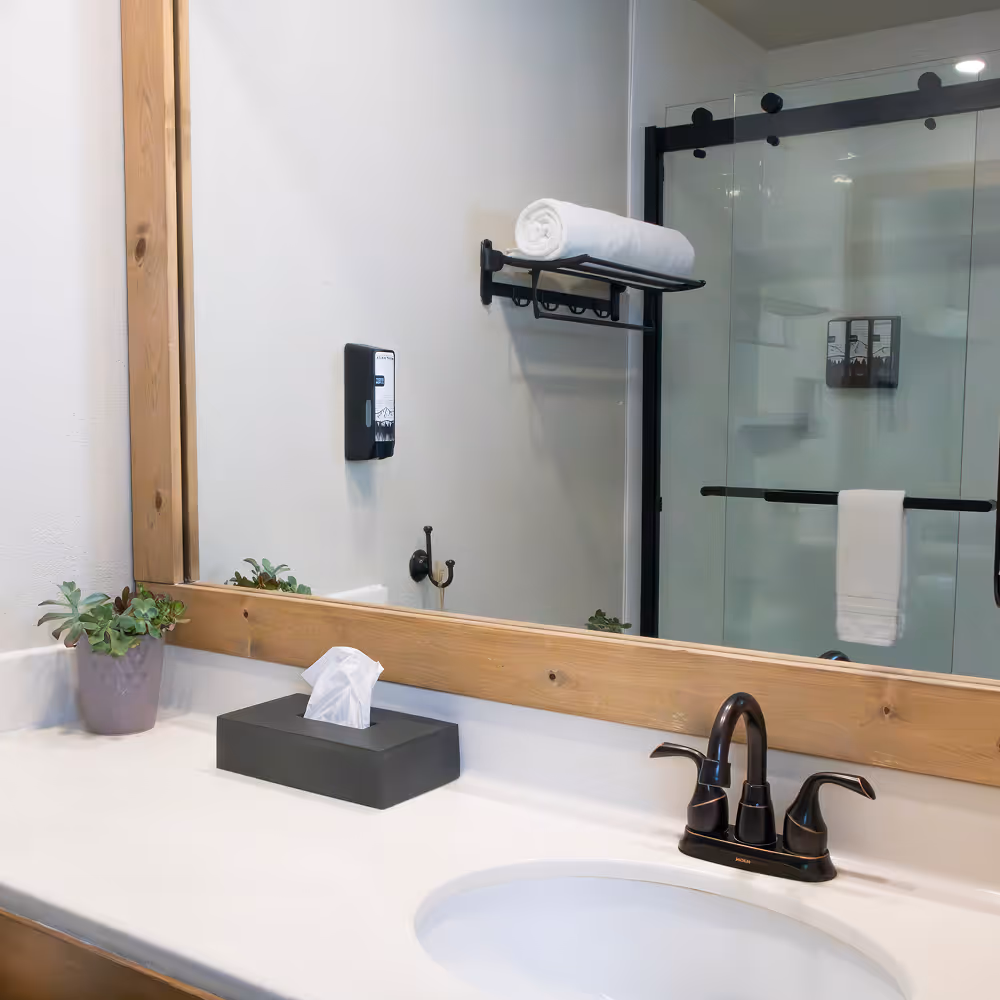The King Room's bathroom — glass-door walk-in shower and a wood-framed mirror.