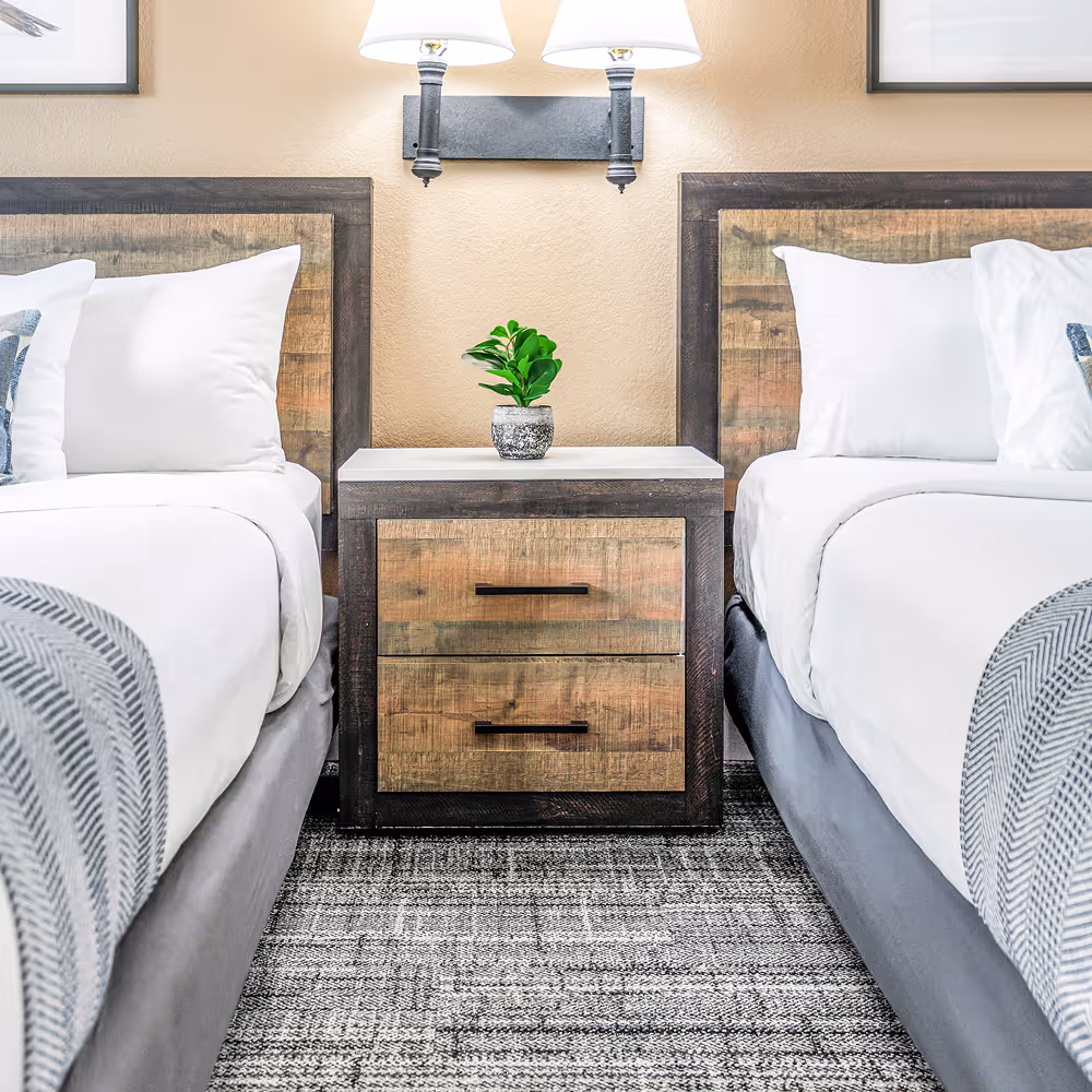 The space between the beds — reclaimed-wood headboards and a shared bedside nook.