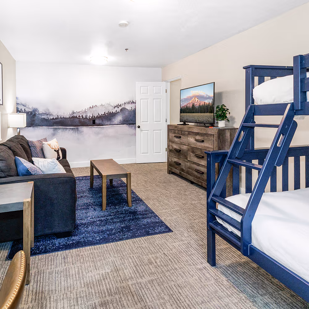 The suite's second sleeping zone — navy bunks, a mountain mural, and a TV for downtime.