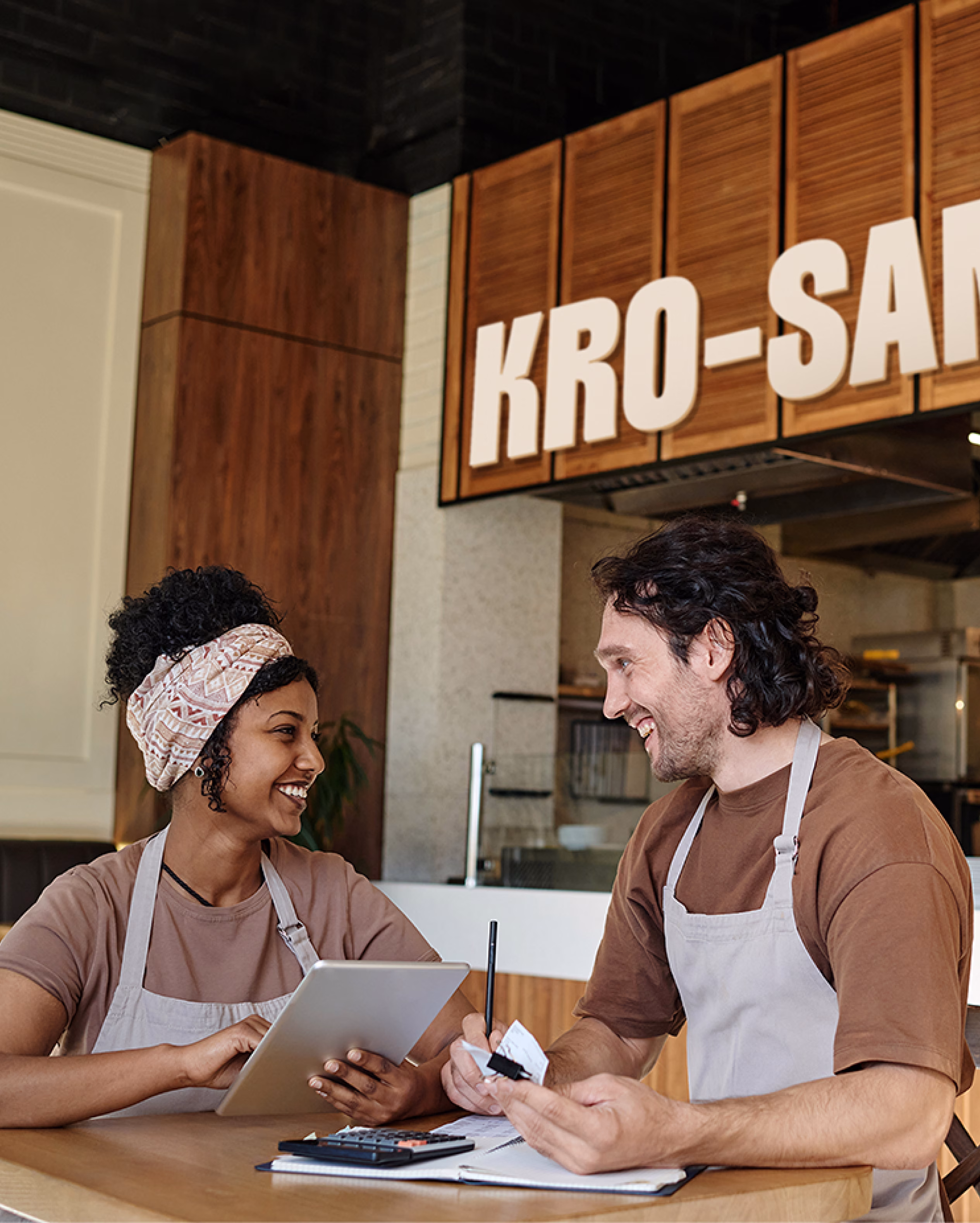 Krosan bakery team members in branded aprons working at store counter by Hatypo