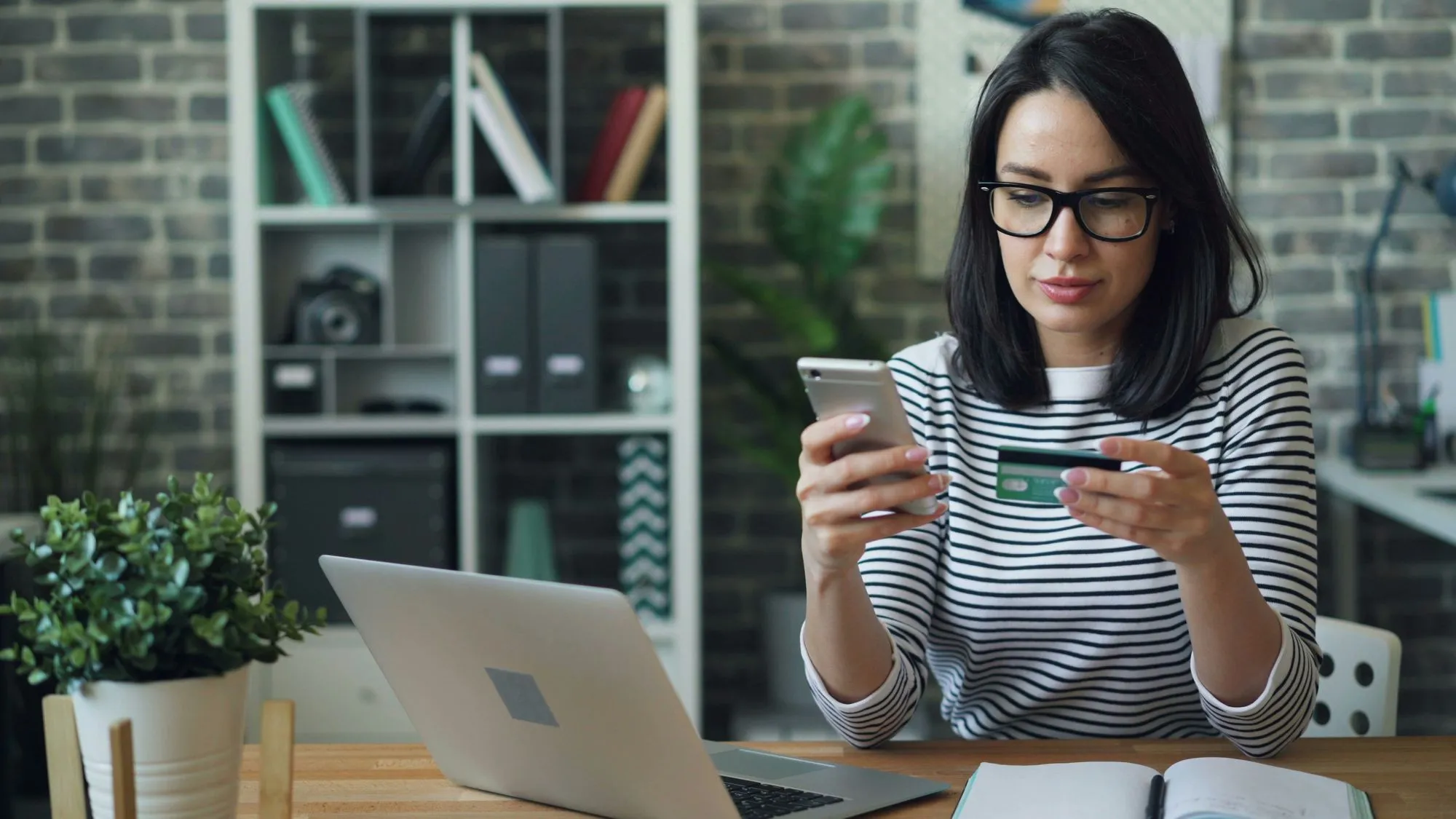 A woman sitting at a table looking at her cell phone.