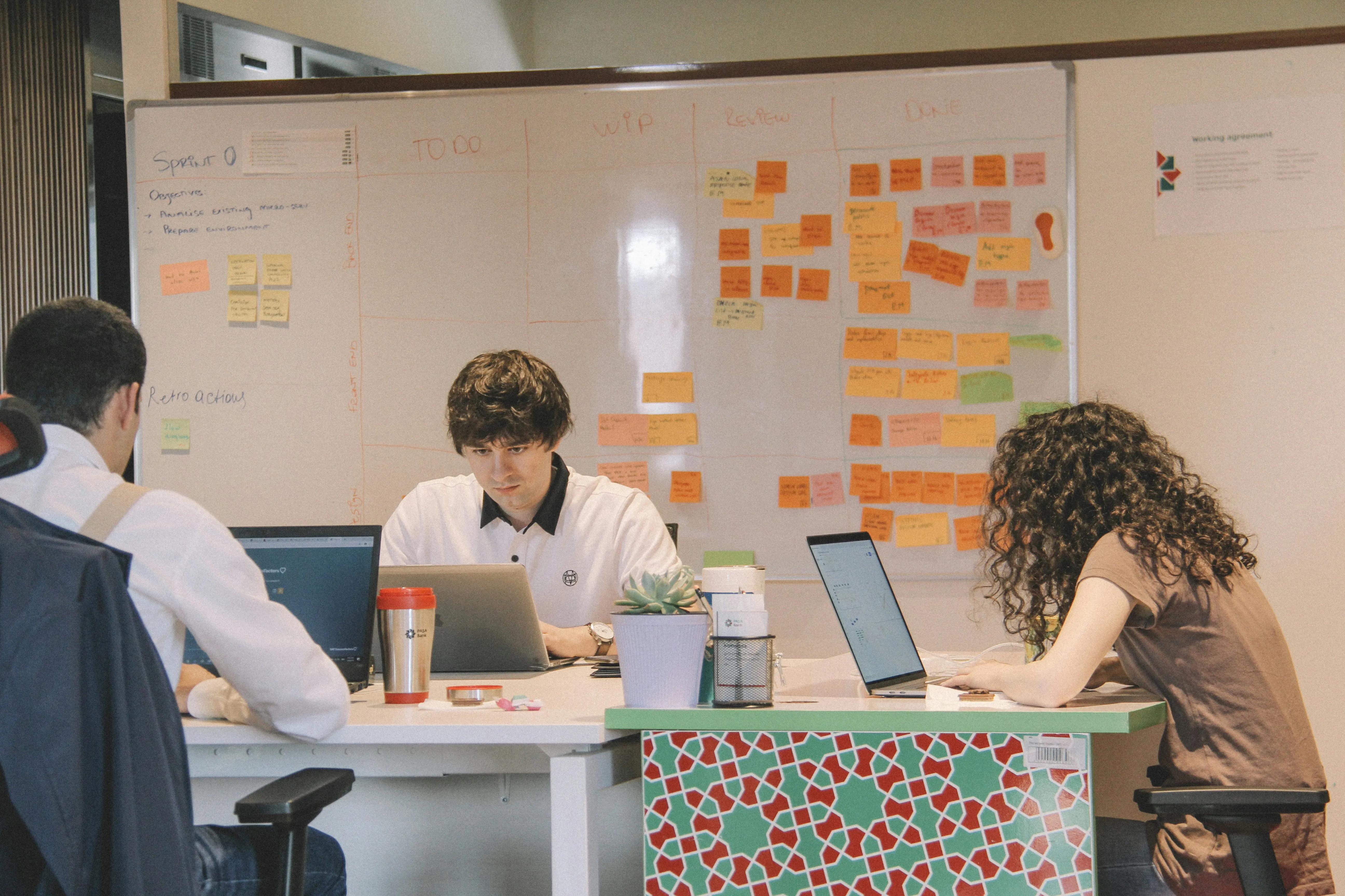 A group of people sitting at a table with laptops.