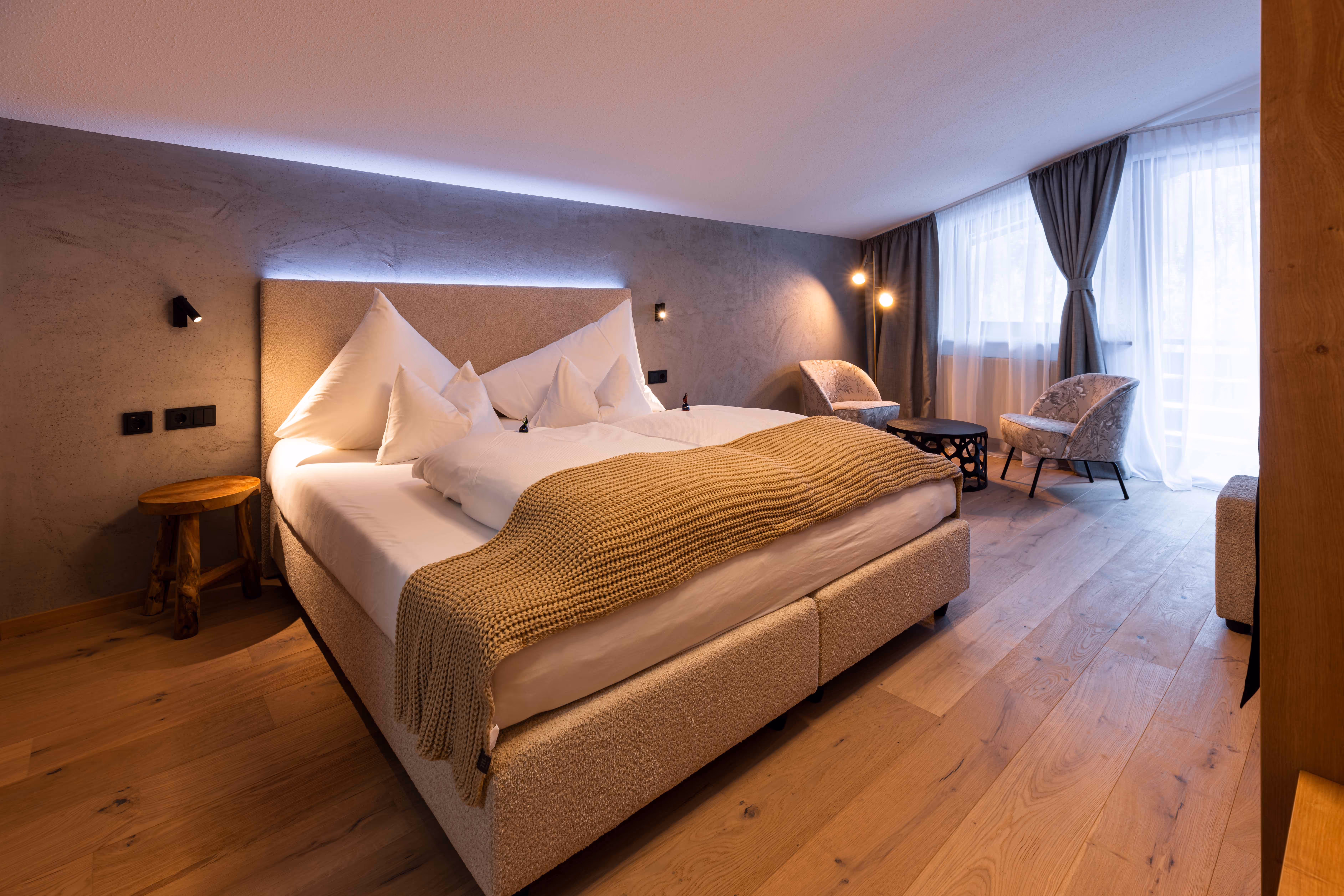Gemütliches Wohlfühlzimmer mit Boxspringbett und warmer Beleuchtung im afoch fei Boutique Hotel St. Anton am Arlberg