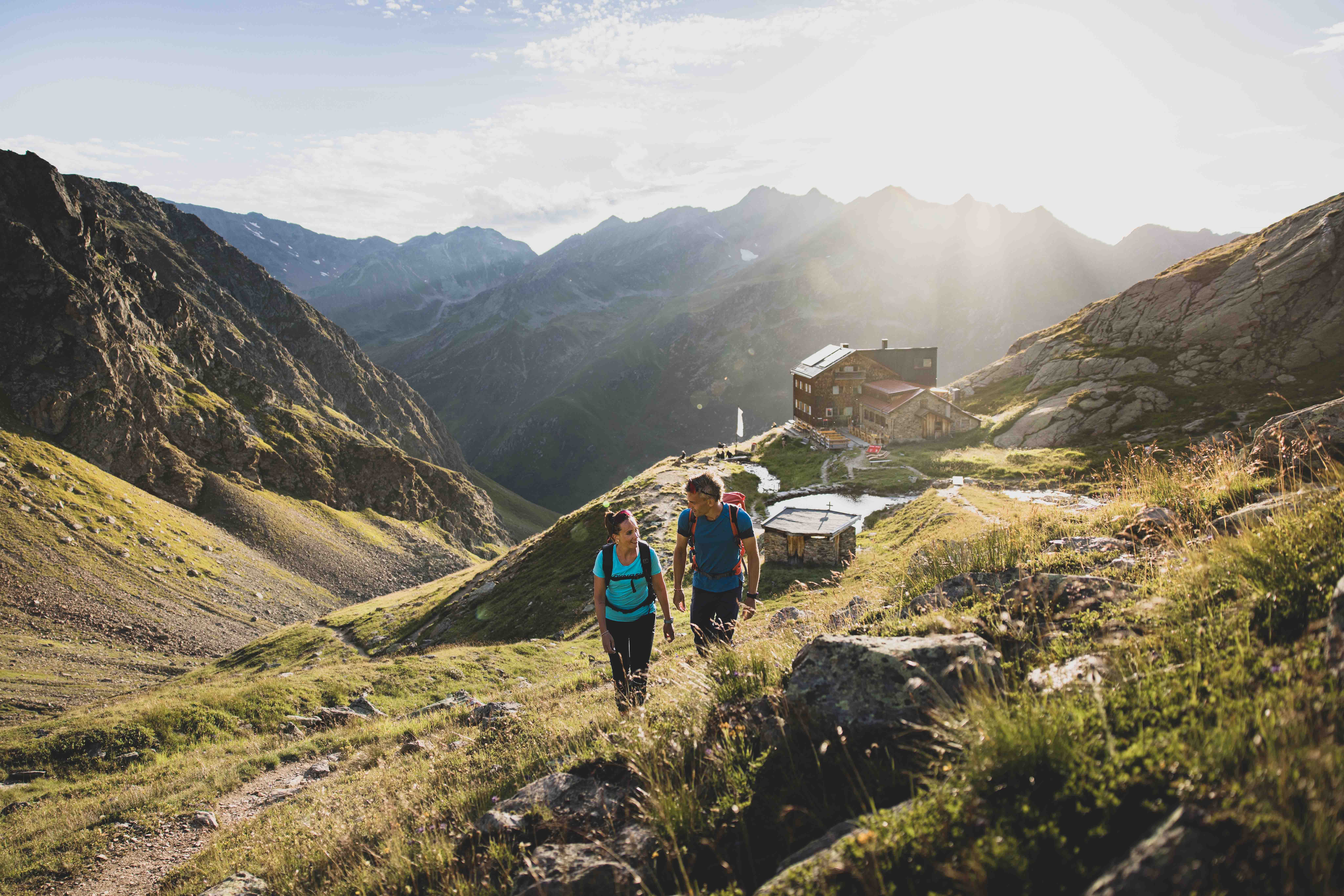 Wanderer auf einem Schotterweg durch ein Bergtal am Arlberg

