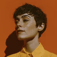 Close-up of a person with short dark hair and a yellow shirt against an orange wall.