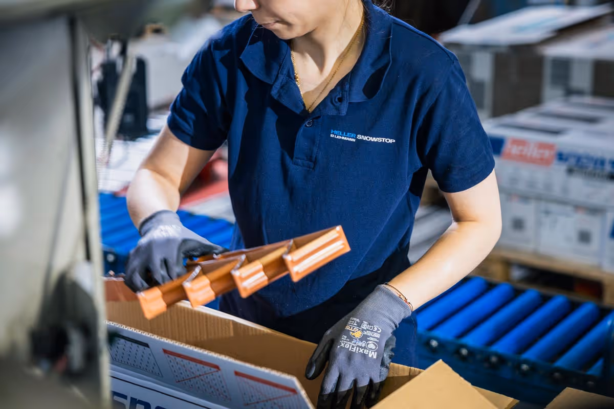 Schwarzweiß-Fabrikhalle mit zahlreichen Arbeitern an Maschinen aus der frühen Industriezeit.
